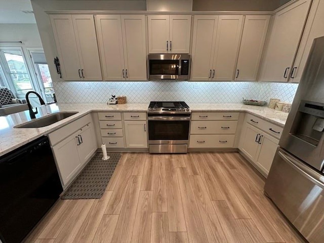 kitchen featuring light stone countertops, white cabinetry, sink, and stainless steel appliances