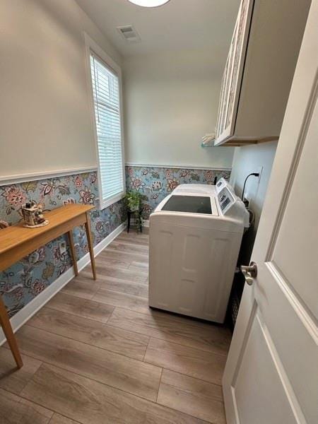 laundry room featuring cabinets, washer / clothes dryer, and light hardwood / wood-style flooring