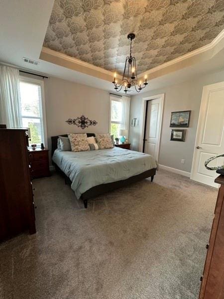 bedroom with a tray ceiling, crown molding, carpet, and a notable chandelier