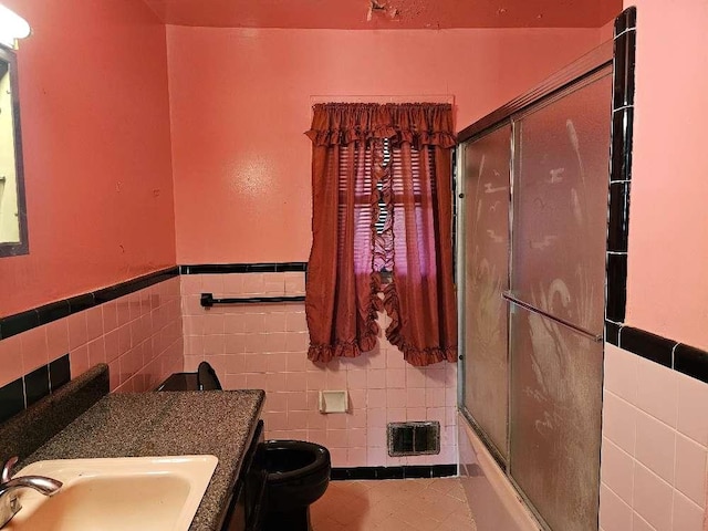 full bathroom featuring toilet, combined bath / shower with glass door, tile walls, vanity, and tile patterned flooring