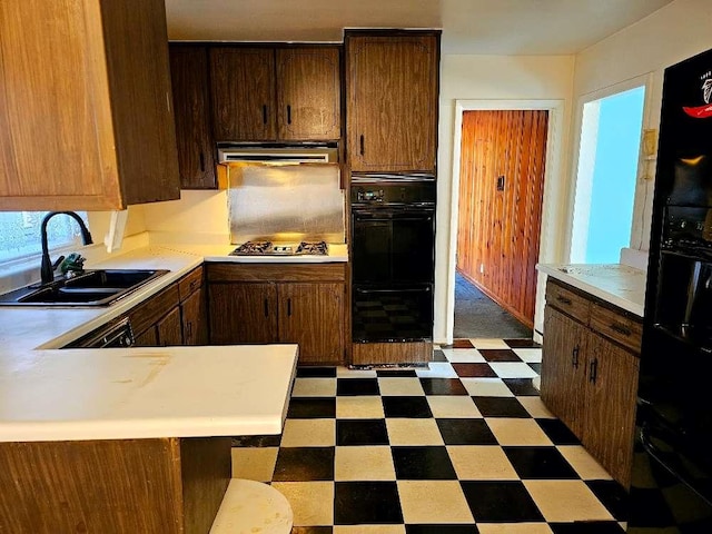 kitchen featuring stainless steel gas stovetop, sink, double oven, and kitchen peninsula