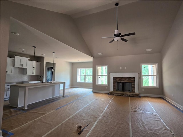 8970 Callaway Dr, Winston, GA 30187 - unfurnished living room with baseboards, a ceiling fan, high vaulted ceiling, a fireplace, and a sink