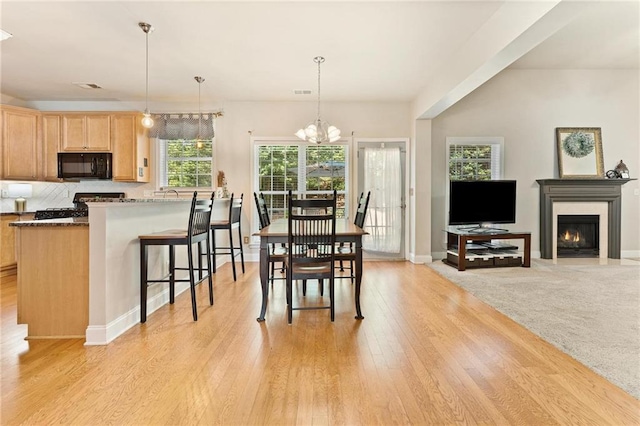 525 Roland Manor Dr, Dacula, GA 30019 - dining area featuring a chandelier, a fireplace with flush hearth, light wood-type flooring, and baseboards