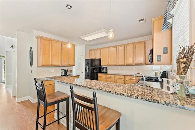 525 Roland Manor Dr, Dacula, GA 30019 - kitchen with black fridge with ice dispenser, light brown cabinetry, tasteful backsplash, and light wood finished floors