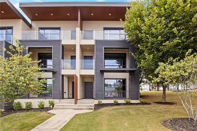 view of front of house with a balcony and a front lawn