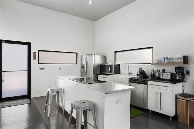 kitchen featuring a center island, white cabinets, sink, appliances with stainless steel finishes, and a kitchen bar