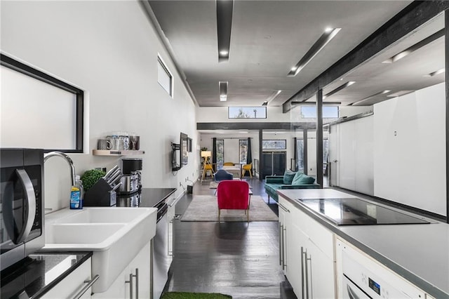 kitchen with white cabinetry, dark hardwood / wood-style flooring, stainless steel appliances, and washer / dryer