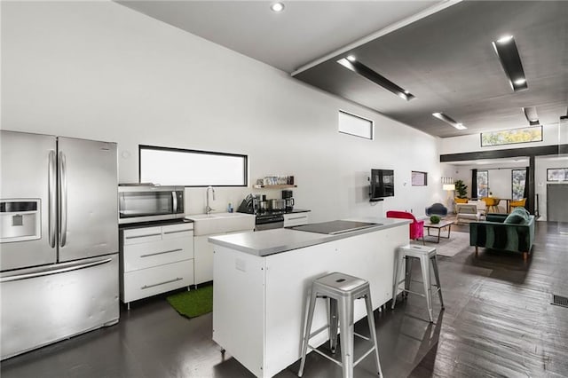 kitchen with appliances with stainless steel finishes, sink, a center island, white cabinetry, and a breakfast bar area