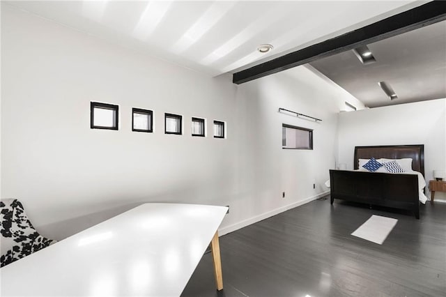 bedroom with beamed ceiling and dark wood-type flooring