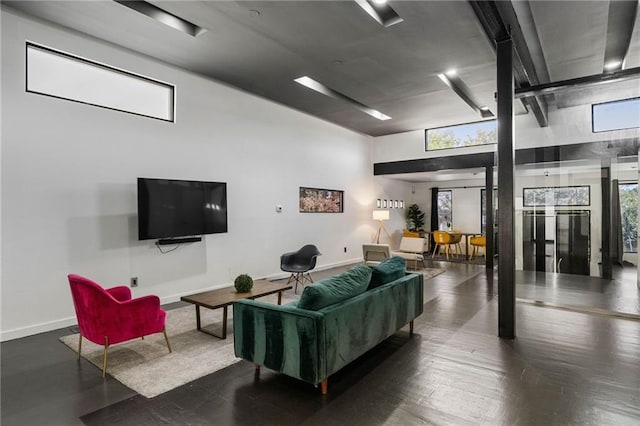 living room with a towering ceiling and dark wood-type flooring