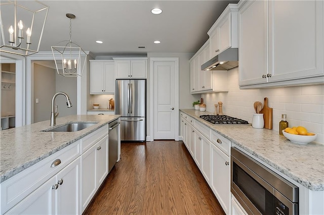 3910 Cameron Ct, Cumming, GA 30040 - kitchen with stainless steel appliances, under cabinet range hood, a sink, a chandelier, and white cabinetry