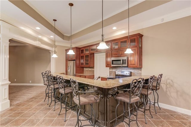 255 Beech Tree Holw, Sugar Hill, GA 30518 - kitchen featuring stainless steel appliances, decorative columns, brown cabinetry, ornamental molding, and a kitchen breakfast bar
