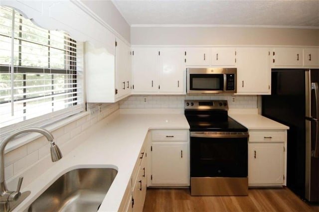 kitchen with sink, dark hardwood / wood-style floors, backsplash, white cabinets, and appliances with stainless steel finishes