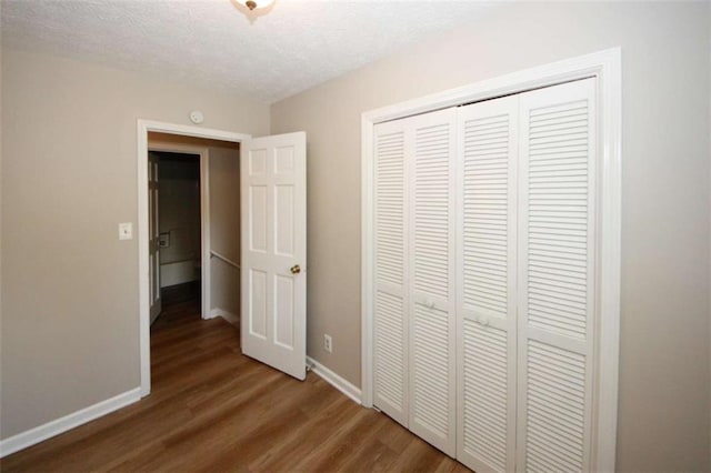 unfurnished bedroom featuring hardwood / wood-style floors, a textured ceiling, and a closet