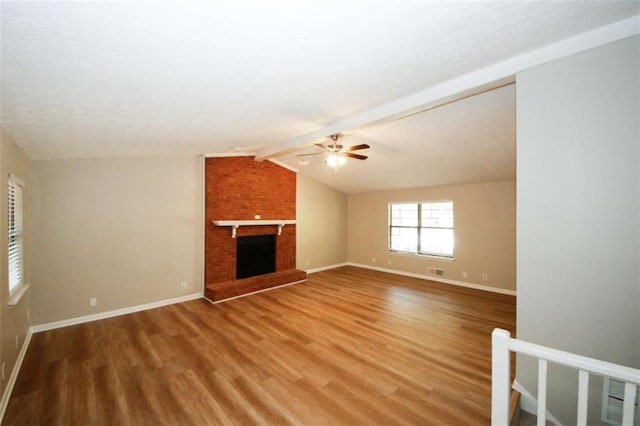 unfurnished living room featuring hardwood / wood-style flooring, vaulted ceiling with beams, ceiling fan, and a brick fireplace