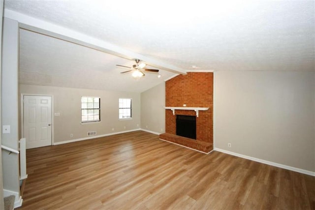 unfurnished living room featuring lofted ceiling with beams, ceiling fan, wood-type flooring, and a brick fireplace