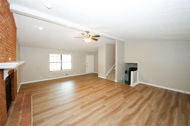 unfurnished living room with ceiling fan, light hardwood / wood-style floors, vaulted ceiling, and a brick fireplace