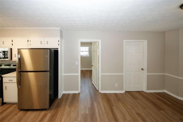 kitchen featuring a textured ceiling, light hardwood / wood-style flooring, range, white cabinetry, and stainless steel refrigerator