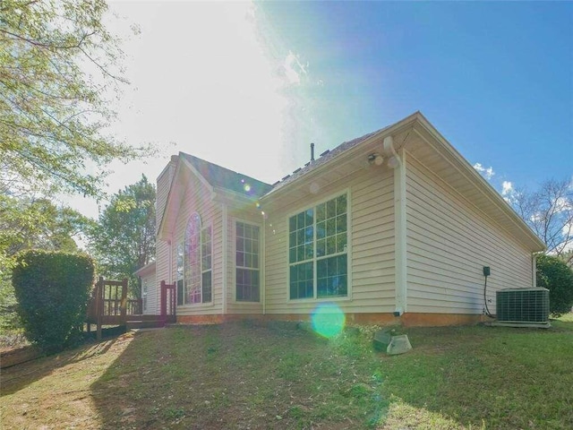 view of property exterior featuring a lawn, central air condition unit, and a wooden deck