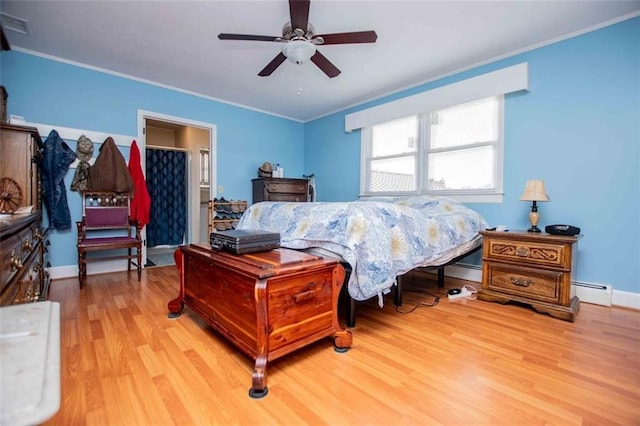 bedroom with crown molding, baseboard heating, and light wood-type flooring