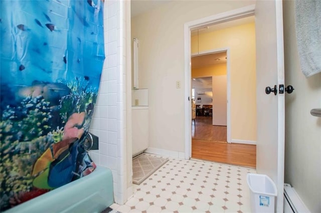 bathroom featuring shower / bath combo and a baseboard heating unit