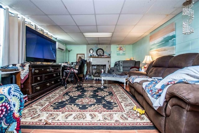 living room featuring a paneled ceiling and an AC wall unit