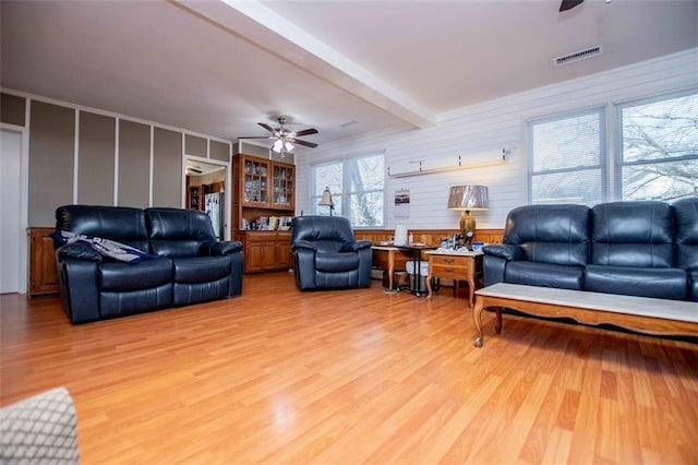 living room featuring beamed ceiling, ceiling fan, and wood-type flooring