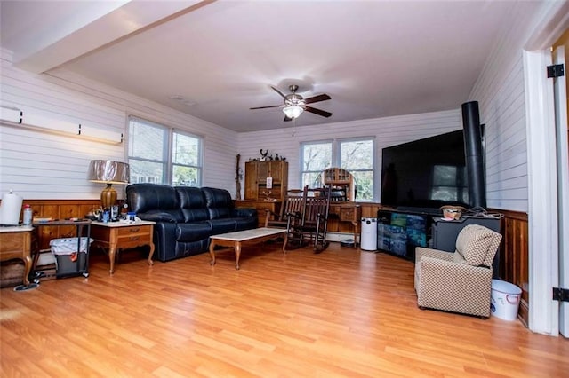 living room with ceiling fan, light hardwood / wood-style flooring, and a wood stove