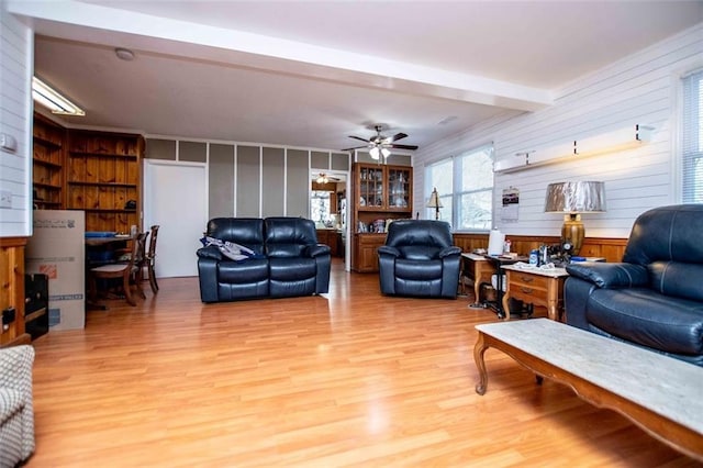 living room with beam ceiling, ceiling fan, and light wood-type flooring