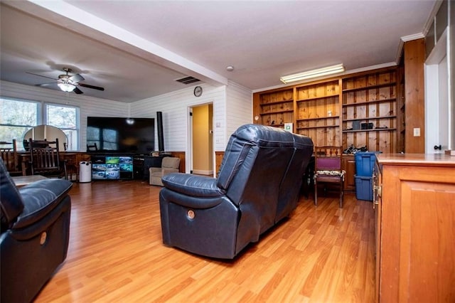 living room with crown molding, ceiling fan, and light wood-type flooring