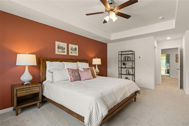 carpeted bedroom featuring a raised ceiling and ceiling fan