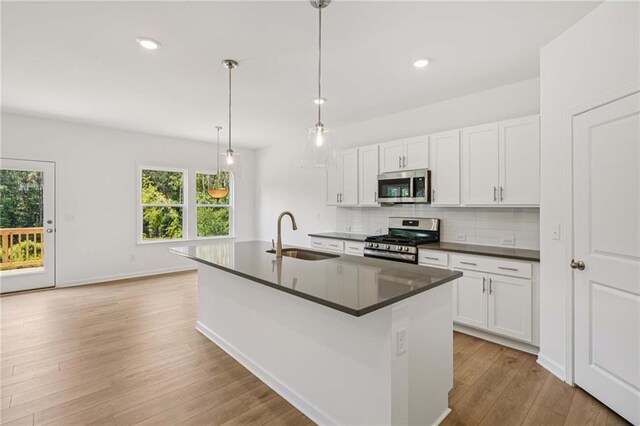 7252 Eton Ln, Locust Grove, GA 30248 - kitchen with open floor plan, white cabinets, a fireplace, hanging light fixtures, and dark stone countertops