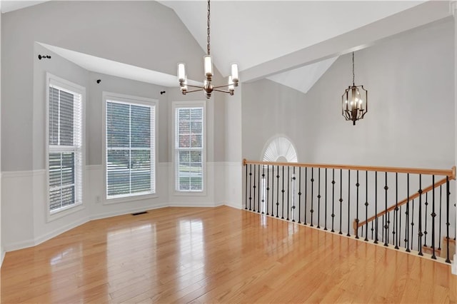 207 Amaranth Ct, Ball Ground, GA 30107 - empty room featuring a chandelier, wood finished floors, wainscoting, healthy amount of natural light, and high vaulted ceiling