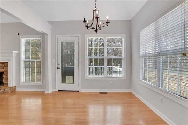 207 Amaranth Ct, Ball Ground, GA 30107 - unfurnished dining area featuring a chandelier, light wood-style floors, lofted ceiling, and a stone fireplace