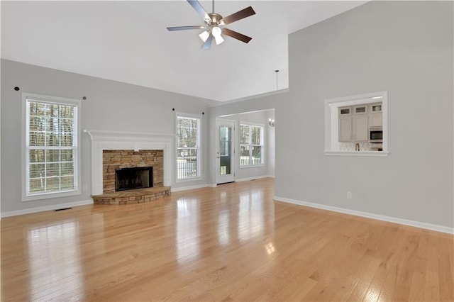 207 Amaranth Ct, Ball Ground, GA 30107 - unfurnished living room featuring light wood-type flooring, a ceiling fan, plenty of natural light, high vaulted ceiling, and a stone fireplace