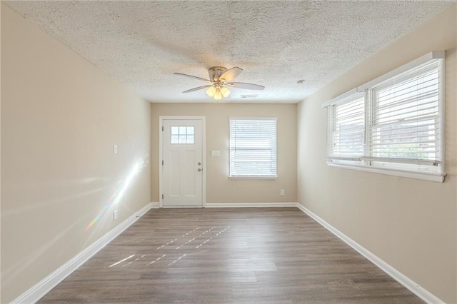 entryway with ceiling fan, a textured ceiling, wood finished floors, and baseboards