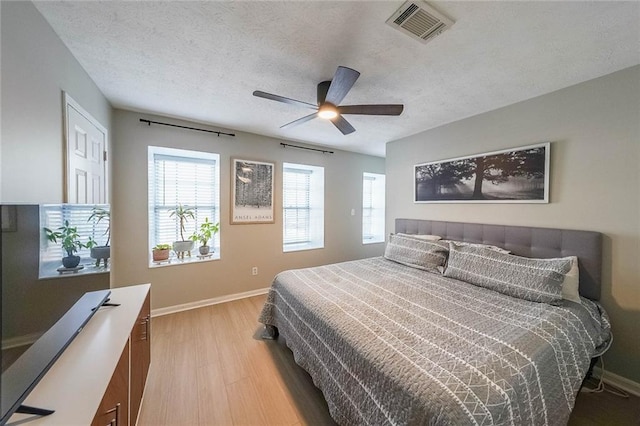 bedroom featuring a textured ceiling, light hardwood / wood-style flooring, and ceiling fan