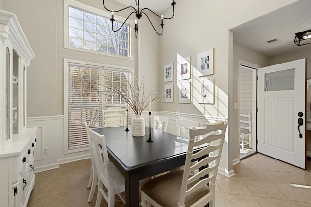 tiled dining space with a towering ceiling and an inviting chandelier