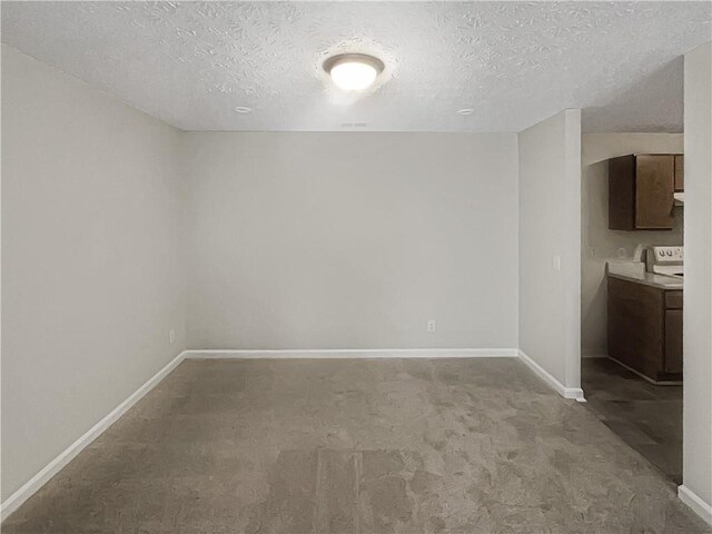 unfurnished room with carpet flooring, washer / clothes dryer, baseboards, and a textured ceiling
