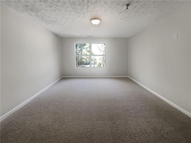spare room with carpet flooring, baseboards, and a textured ceiling