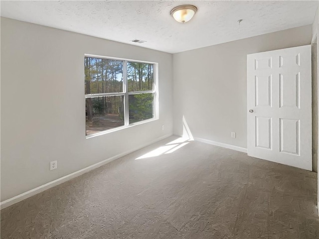 carpeted spare room featuring baseboards, visible vents, and a textured ceiling