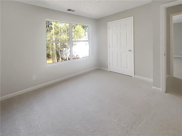 unfurnished bedroom with baseboards, carpet flooring, a textured ceiling, and visible vents