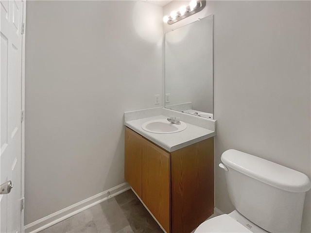 half bathroom with toilet, vanity, and baseboards