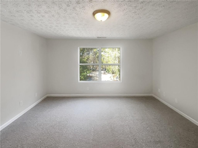 carpeted empty room featuring baseboards, visible vents, and a textured ceiling