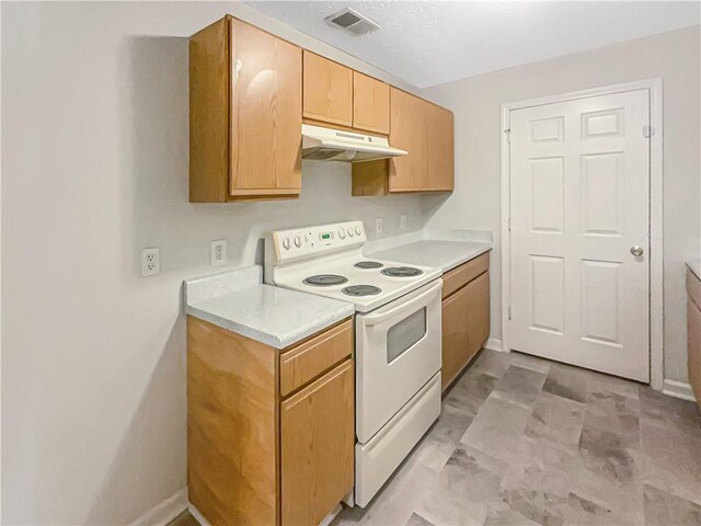 kitchen with light countertops, under cabinet range hood, baseboards, visible vents, and electric range