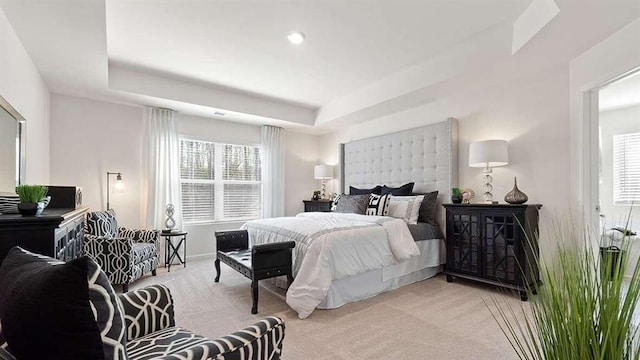 bedroom featuring light carpet and a tray ceiling