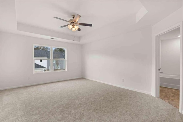 unfurnished room featuring carpet, ceiling fan, and a raised ceiling