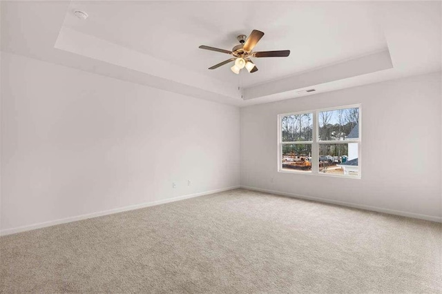 spare room featuring ceiling fan, carpet flooring, and a tray ceiling