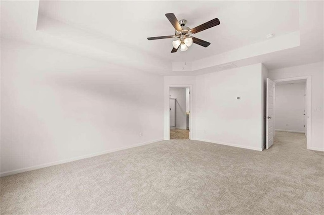 carpeted empty room with ceiling fan and a raised ceiling