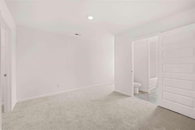 unfurnished bedroom with light carpet and connected bathroom